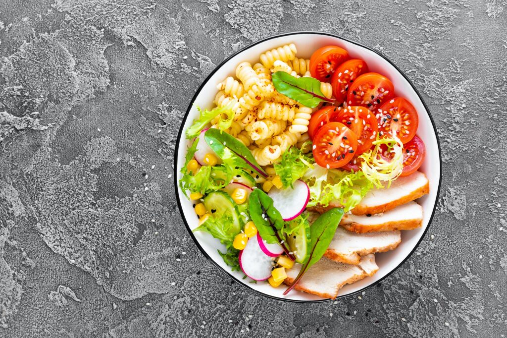 Grilled chicken meat with fresh vegetable salad and pasta