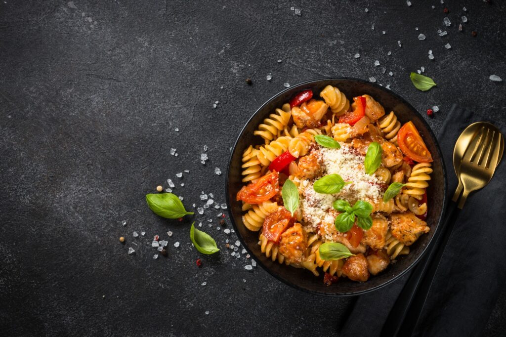 Pasta chicken with vegetables on black.