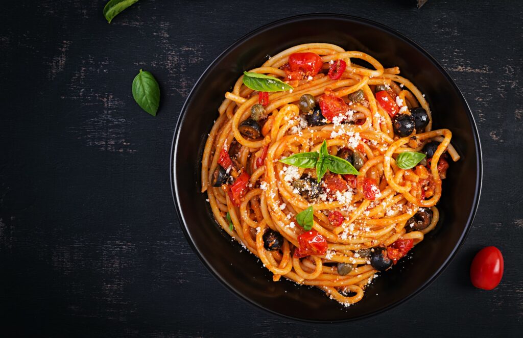 Spaghetti alla puttanesca - italian pasta dish with tomatoes, black olives, capers