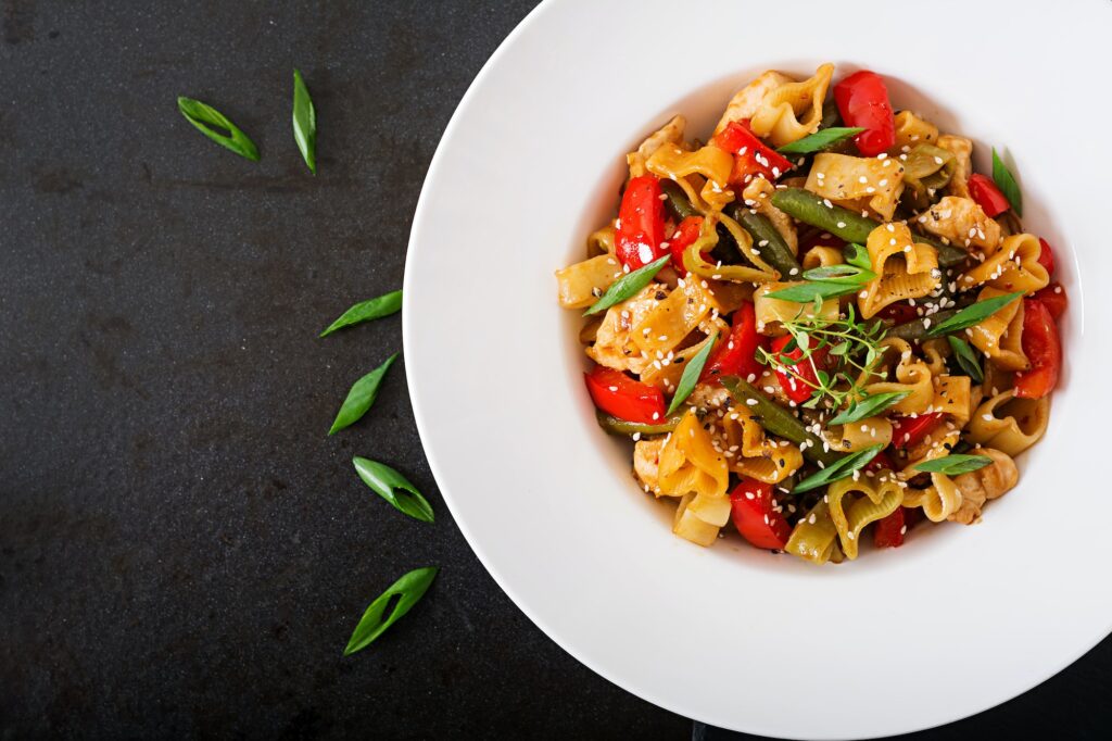 Stir Fry from chicken fillet, green beans and paprika with pasta