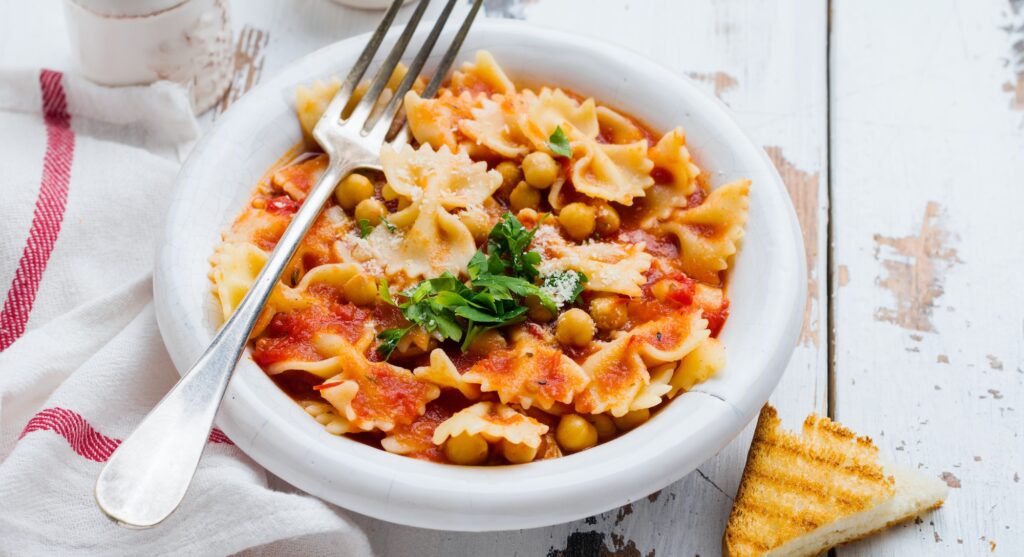 Traditional Italian dish, chowder, pottage, pasta e ceci served in old plate on old wooden backgroun