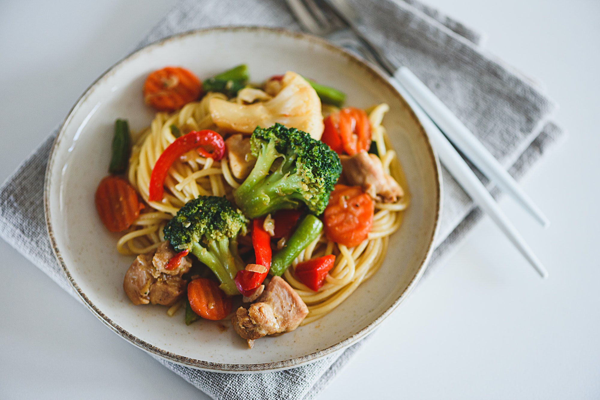 Whole wheat organic pasta with vegetables on white wooden table