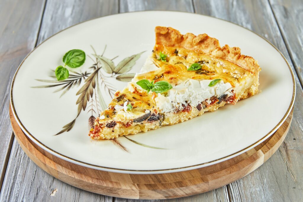 Piece of quiche with goat cheese on plate. French gourmet cuisine